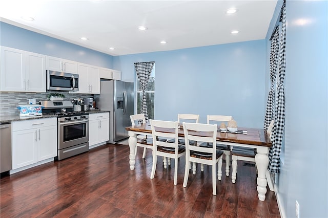 kitchen with white cabinetry, tasteful backsplash, dark hardwood / wood-style floors, dark stone countertops, and appliances with stainless steel finishes