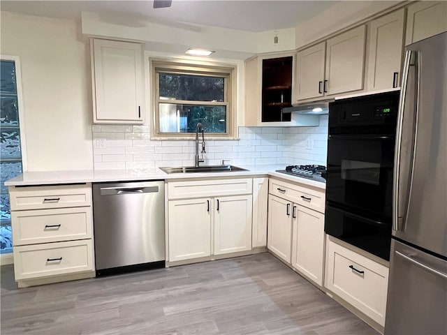 kitchen featuring black appliances, white cabinets, sink, tasteful backsplash, and light hardwood / wood-style floors