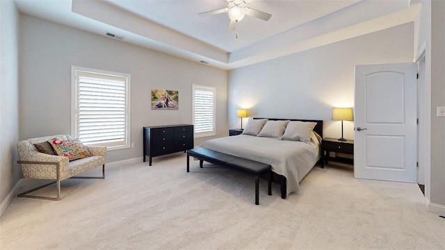 carpeted bedroom with a tray ceiling and ceiling fan