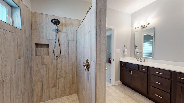 bathroom with a tile shower and vanity