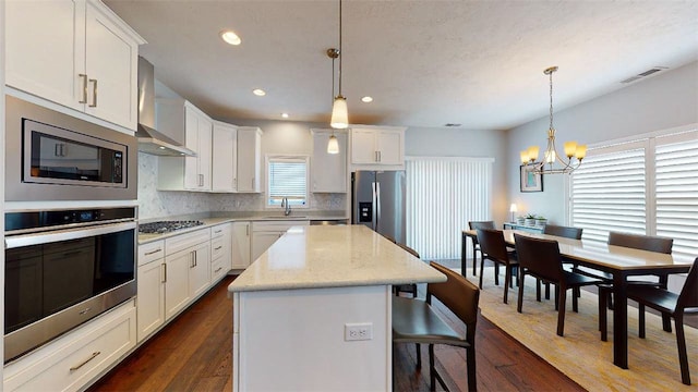 kitchen featuring dark hardwood / wood-style floors, a center island, decorative light fixtures, and appliances with stainless steel finishes