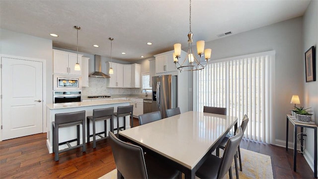 dining space with sink, dark wood-type flooring, and an inviting chandelier