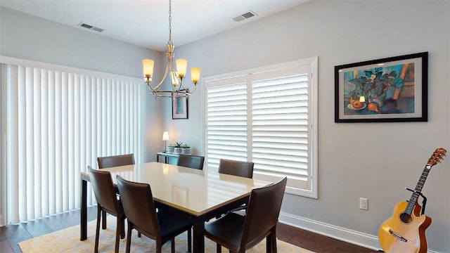 dining area with dark wood-type flooring and a notable chandelier