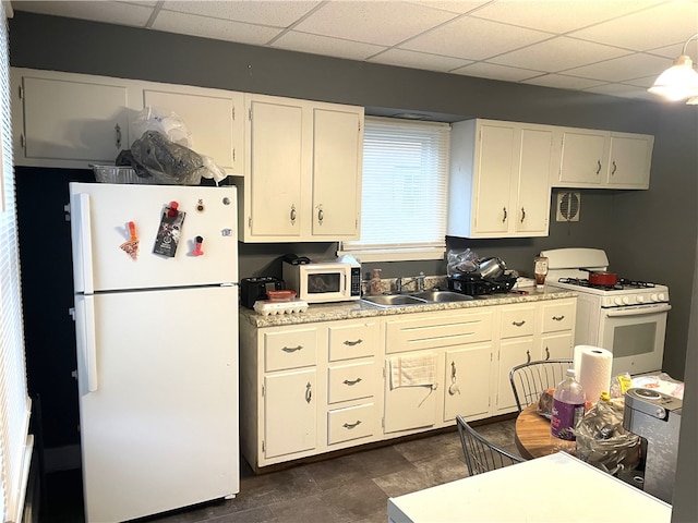 kitchen featuring a paneled ceiling, white cabinets, white appliances, and sink