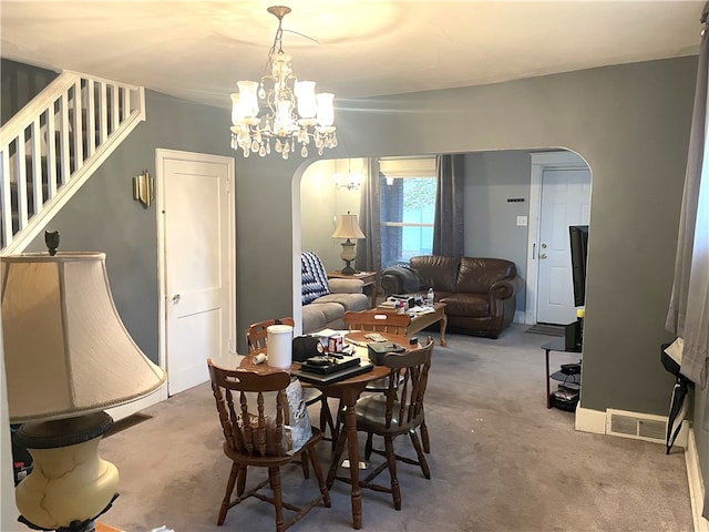 carpeted dining room with a chandelier