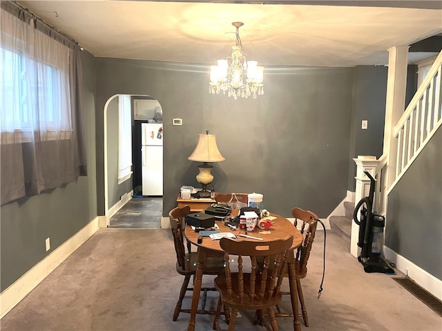 carpeted dining space with a chandelier