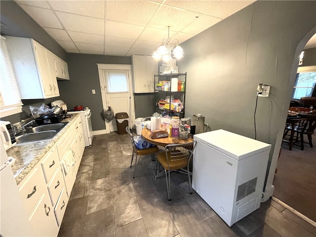 kitchen featuring white cabinetry, sink, hanging light fixtures, plenty of natural light, and fridge