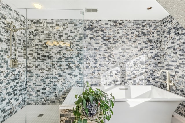 bathroom featuring plus walk in shower and tile walls