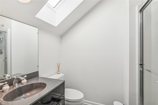 bathroom featuring a skylight, vanity, a shower with shower door, and toilet