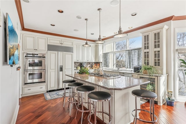 kitchen featuring light stone countertops, a healthy amount of sunlight, hanging light fixtures, and stainless steel appliances