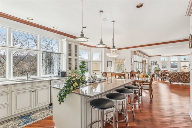 kitchen featuring hanging light fixtures, sink, dark wood-type flooring, and ornamental molding