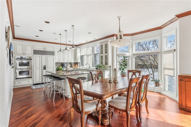 dining area with crown molding, sink, and hardwood / wood-style flooring