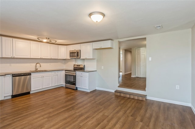 kitchen with sink, decorative backsplash, dark hardwood / wood-style flooring, white cabinetry, and stainless steel appliances