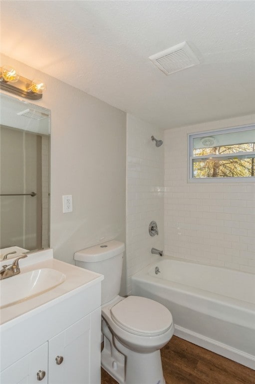 full bathroom with hardwood / wood-style floors, vanity, tiled shower / bath combo, and toilet