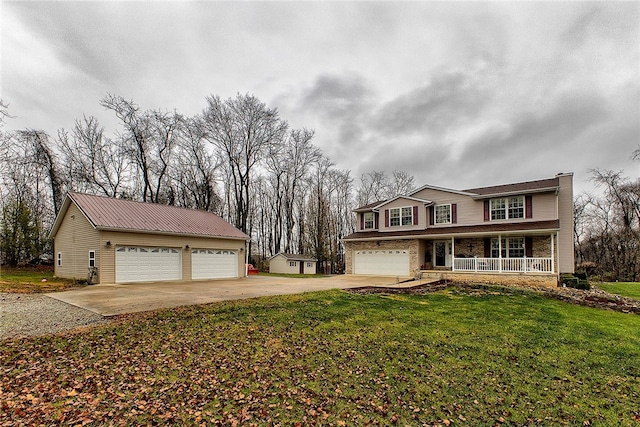 view of front of home featuring a garage, covered porch, an outbuilding, and a front lawn