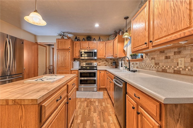 kitchen featuring pendant lighting, light hardwood / wood-style floors, sink, and stainless steel appliances