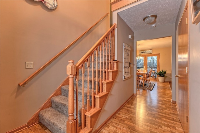 stairs with french doors, hardwood / wood-style floors, and a textured ceiling