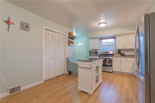 kitchen with a kitchen island, white cabinetry, appliances with stainless steel finishes, and light hardwood / wood-style flooring