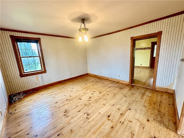 empty room featuring hardwood / wood-style flooring, an inviting chandelier, and ornamental molding