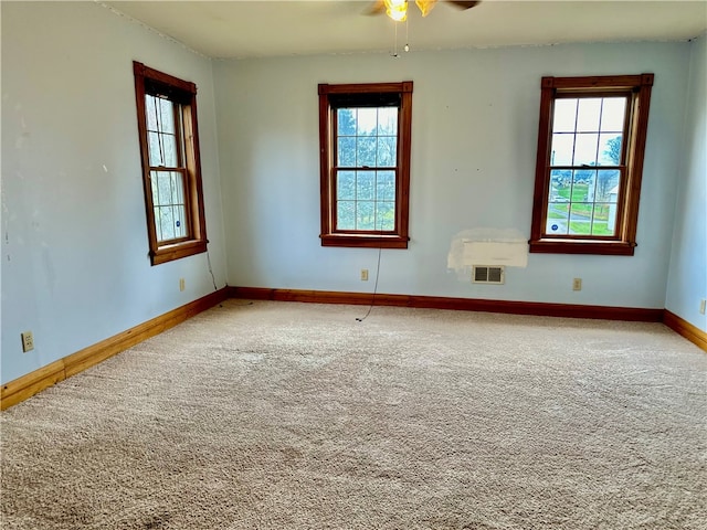 carpeted empty room with a wealth of natural light and ceiling fan