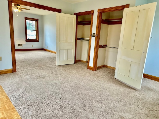 unfurnished bedroom with multiple closets, ceiling fan, and carpet floors