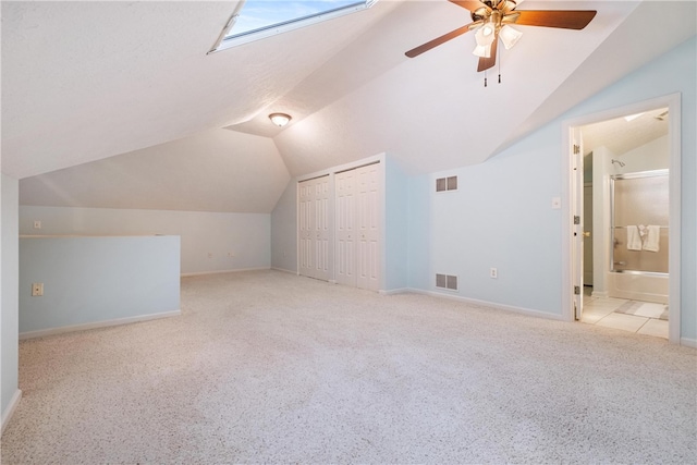 bonus room with ceiling fan, light colored carpet, and lofted ceiling with skylight