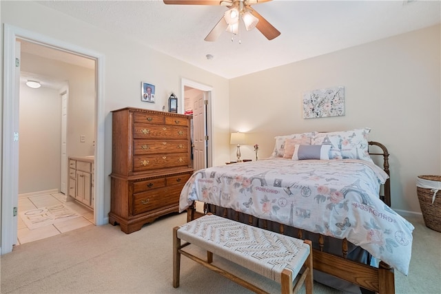 bedroom featuring light carpet, a walk in closet, ensuite bath, ceiling fan, and a closet