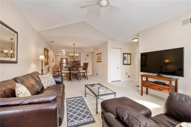 carpeted living room with ceiling fan with notable chandelier and vaulted ceiling