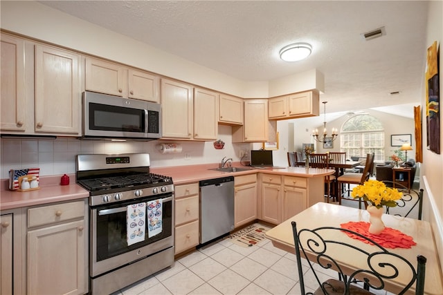 kitchen with sink, stainless steel appliances, a textured ceiling, decorative light fixtures, and light tile patterned floors