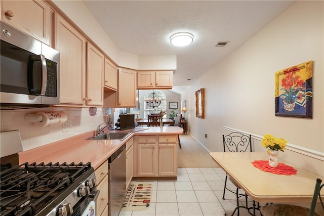 kitchen featuring light brown cabinets, sink, light tile patterned floors, a textured ceiling, and stainless steel appliances