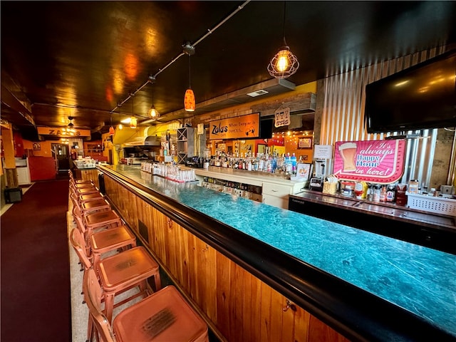 bar with hanging light fixtures, dark carpet, and track lighting