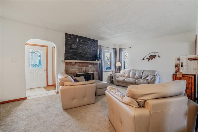 carpeted living room featuring a textured ceiling and a stone fireplace