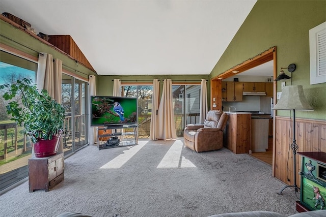 living room featuring light carpet, high vaulted ceiling, and wood walls