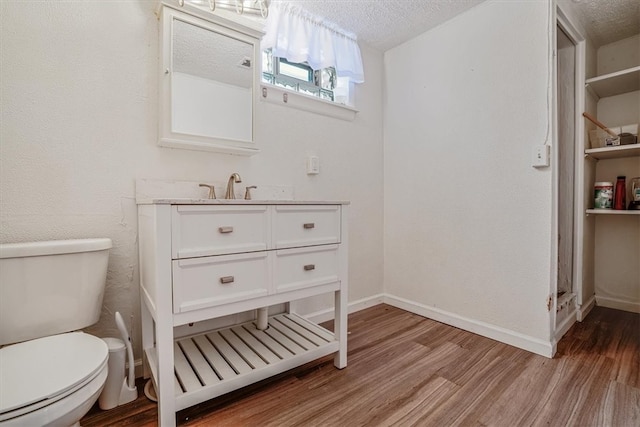 bathroom with toilet, vanity, a textured ceiling, and hardwood / wood-style flooring