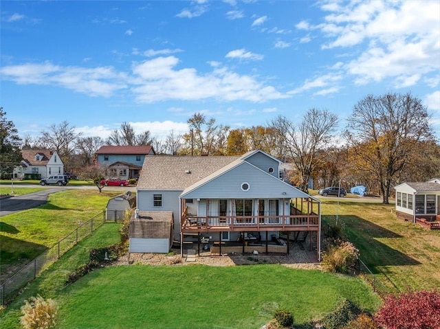 rear view of property featuring a lawn, a storage shed, and a deck