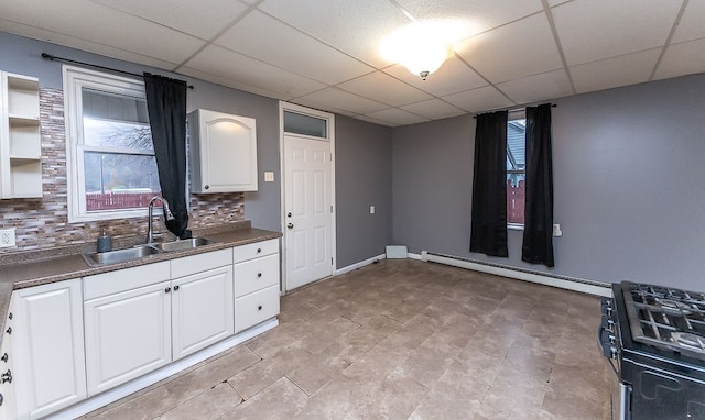 kitchen with a paneled ceiling, tasteful backsplash, sink, a baseboard radiator, and white cabinets