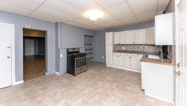 kitchen with stainless steel gas range oven, white cabinetry, sink, and decorative backsplash