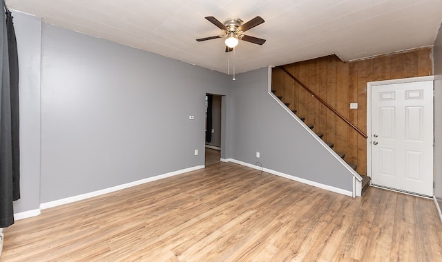 interior space featuring light hardwood / wood-style floors, ceiling fan, and wood walls