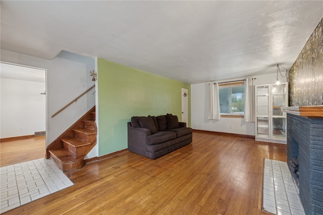 living room featuring wood-type flooring and a brick fireplace