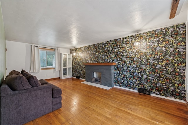 living room with a fireplace, beamed ceiling, and wood-type flooring