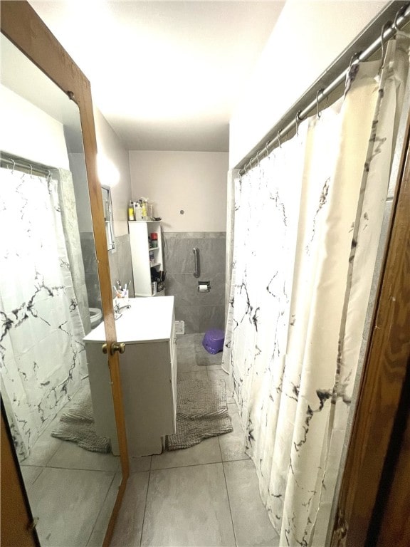 bathroom with tile patterned flooring, vanity, tile walls, and walk in shower