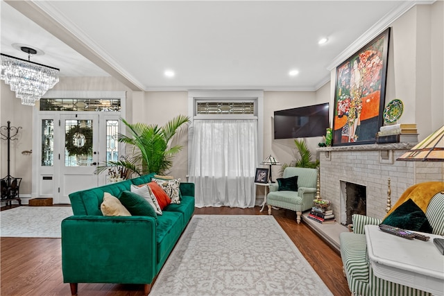 living room with crown molding, wood-type flooring, a fireplace, and an inviting chandelier