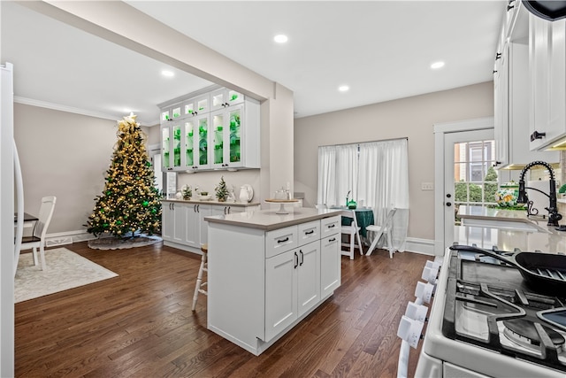 kitchen featuring dark hardwood / wood-style flooring, crown molding, sink, white cabinets, and a kitchen island