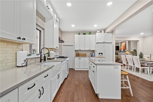 kitchen featuring white cabinetry, tasteful backsplash, dark hardwood / wood-style floors, white appliances, and a kitchen island