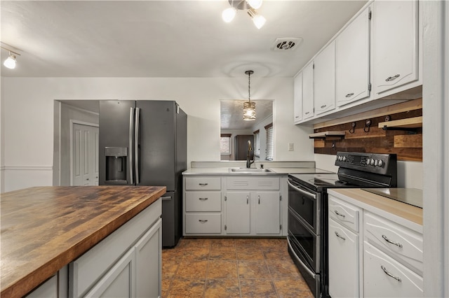 kitchen featuring wooden counters, appliances with stainless steel finishes, sink, white cabinets, and hanging light fixtures