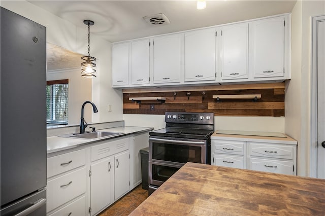 kitchen with hanging light fixtures, white cabinetry, sink, and stainless steel appliances