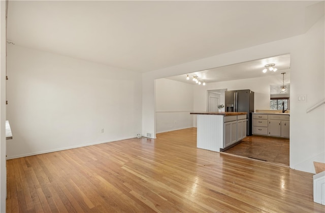 interior space with light hardwood / wood-style floors, stainless steel refrigerator with ice dispenser, and a chandelier