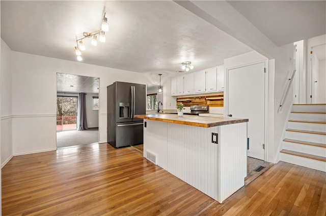 kitchen featuring butcher block counters, sink, stainless steel appliances, white cabinets, and light wood-type flooring