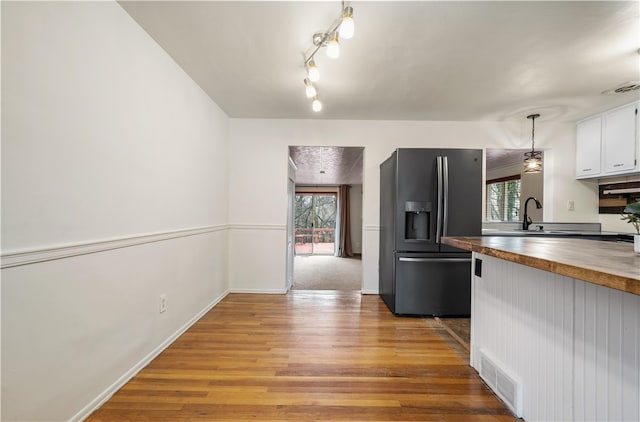 kitchen featuring butcher block countertops, plenty of natural light, light wood-type flooring, and stainless steel fridge with ice dispenser