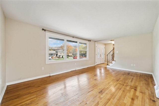 unfurnished living room with hardwood / wood-style floors and baseboard heating